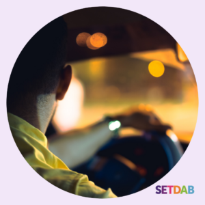 back of man in car with hand on steering wheel